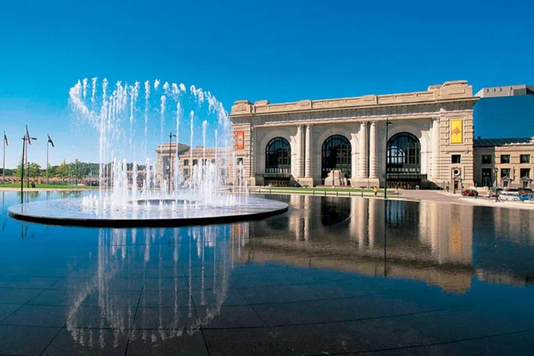 A wide-angle view of the iconic Union Station in Kansas City, Missouri, with the large outdoor fountain reflecting the h