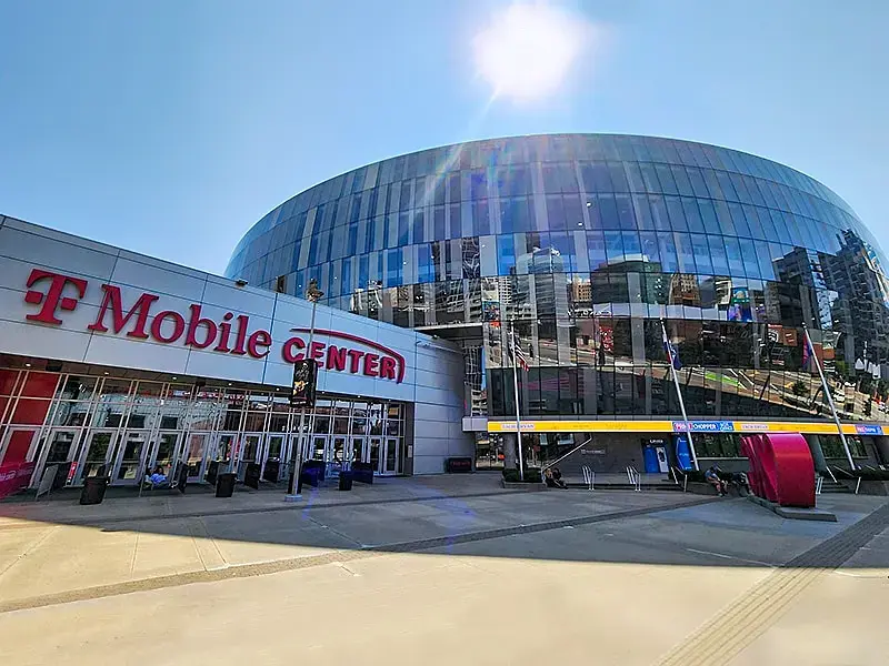 The T-Mobile Center in Kansas City featuring its modern glass facade and large entrance plaza on a bright, sunny day.