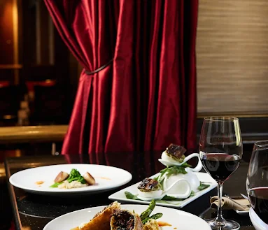 Gourmet dishes and red wine on a table, highlighting the romantic atmosphere of a luxury fine dining restaurant in Kansa