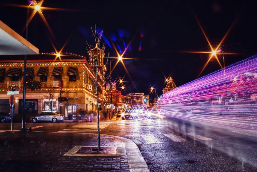 Kansas City Holiday Lights: Luxury Stays & Event Spaces A vibrant night photograph capturing a Kansas City street corner illuminated by holiday lights with striking purple ligh