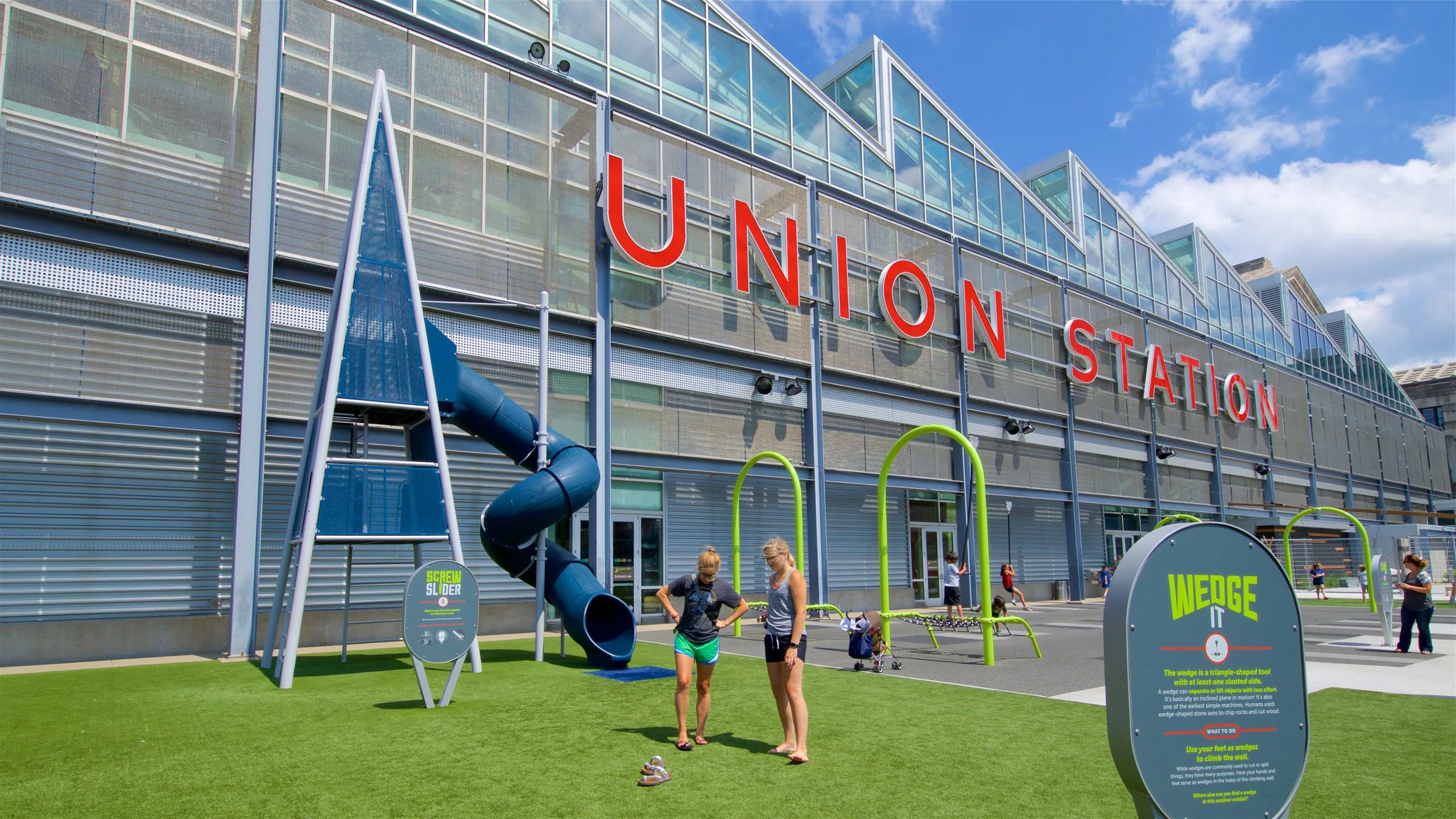 The exterior of the Union Station building in Kansas City featuring large red signage overlooking a modern, turf-covered