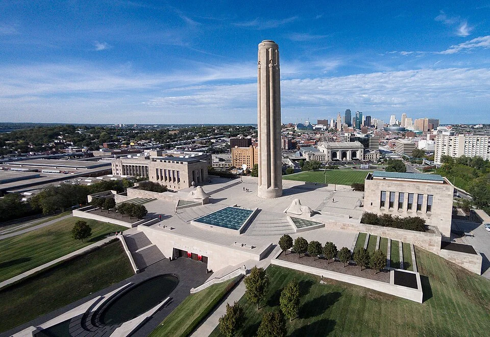 Aerial view of the tall central memorial tower and grounds overlooking the Kansas City downtown skyline on a clear day.