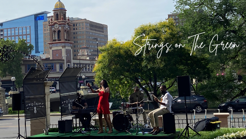 A band performs live jazz music on an outdoor stage at the Country Club Plaza in Kansas City, with a female vocalist.